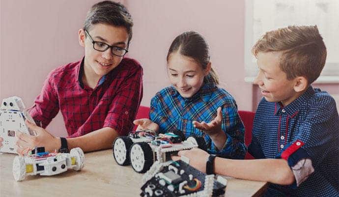Foto de tres niños montando un robot educativo